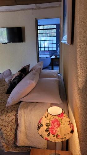 a bedroom with two beds and a table with a lamp at Suítes La Reserve in Campos do Jordão