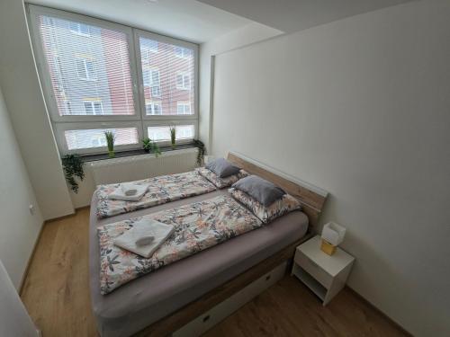 a small bedroom with a bed and two windows at Spirit apartments Brno, with parking in Brno