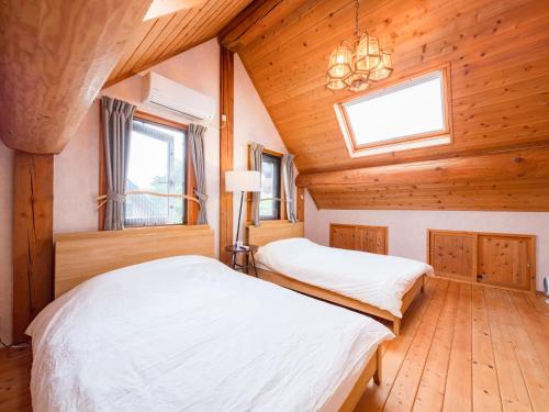 two beds in a room with wooden walls at 八ヶ岳 HOKUTO BASE -Yatsugatake- in Hokuto