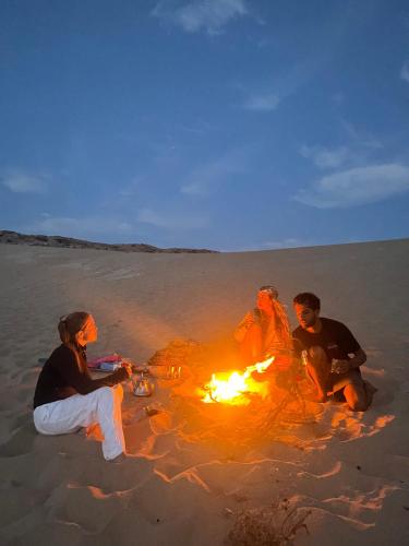 a group of people sitting around a fire on the beach at Imsouane Vibe Surf house in Imsouane
