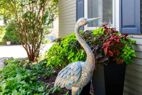 a statue of a bird standing next to a flower pot at Crane Haven - Walk to CyRide Games & Grill in Ames