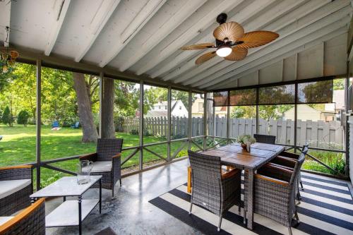 a screened porch with a ceiling fan and a table and chairs at Crane Haven - Walk to CyRide Games & Grill in Ames