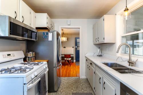 a kitchen with white cabinets and a stainless steel refrigerator at Crane Haven - Walk to CyRide Games & Grill in Ames