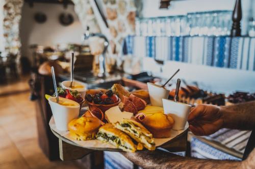 a person holding a tray of food on a table at Limeri Traditional Guest House in Monólithos