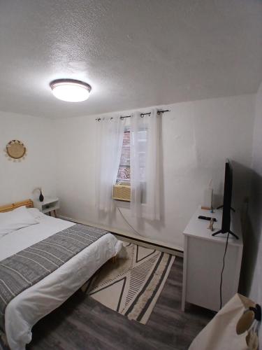 a white bedroom with a bed and a television at A Quiet Spot in Bloomfield, NJ in Bloomfield