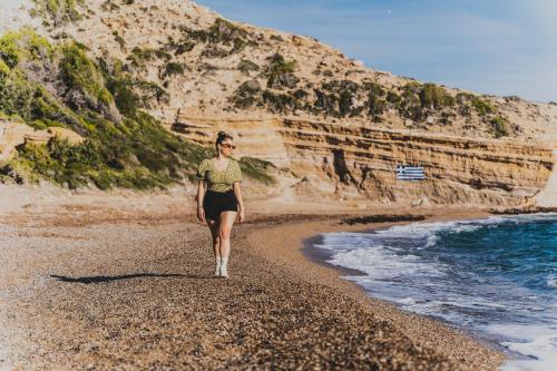 a woman walking on a beach near the ocean at Limeri Traditional Guest House in Monólithos