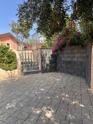 a brick walkway with pink flowers on a fence at La Casetta di Lollò in Aci SantʼAntonio