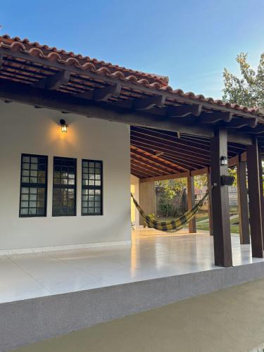 a house with a porch with a hammock on it at Pousada Aromas do Vale in Chapada dos Guimarães