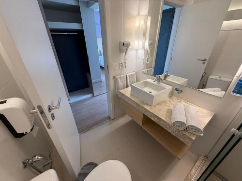 a bathroom with a sink and a toilet and a mirror at Stay Inn Santos Sua acomodação com cara de Hotel in Santos