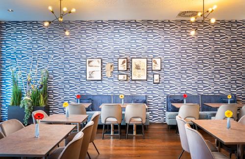 a restaurant with tables and chairs and a blue and white wall at Leonardo Hotel Vienna Hauptbahnhof in Vienna