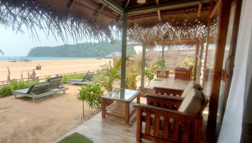 a porch of a beach house with chairs and a table at The Coast Beach Resort in Agonda