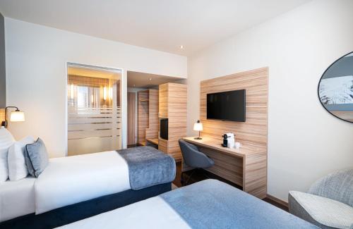 a hotel room with two beds and a desk at Leonardo Hotel Vienna Hauptbahnhof in Vienna