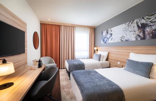 a hotel room with two beds and a tv at Leonardo Hotel Vienna Hauptbahnhof in Vienna