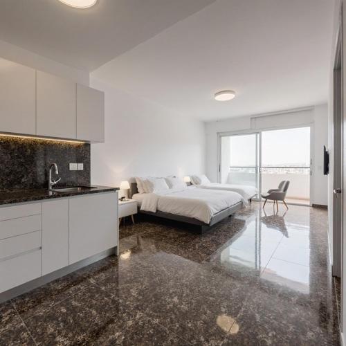 a white bedroom with a bed and a kitchen at House close to airport in El Prat de Llobregat