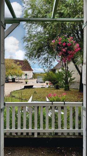 a white fence with a tree with pink flowers at Le Cormier in Obterre