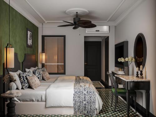 a bedroom with a bed and a desk and a ceiling fan at L'Heritage Riverside Hoi An in Hoi An