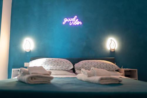 a bedroom with a bed with two pillows and a neon sign at Altopiano Rooms Suite in Foggia
