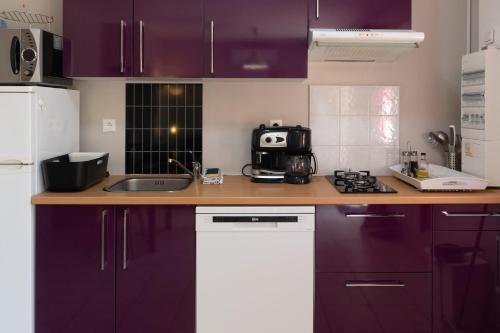 a kitchen with purple cabinets and a sink at Gîte Chêne ou Murier in Les Vans