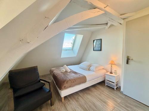 a bedroom with a bed and a chair in a attic at Le Douare, Proche centre-ville, Parking in Morestel
