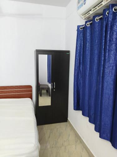 a bedroom with blue curtains and a bed and a mirror at Rest N' Refresh Homes in Visakhapatnam