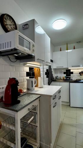 a kitchen with white cabinets and a microwave at Le Cormier in Obterre