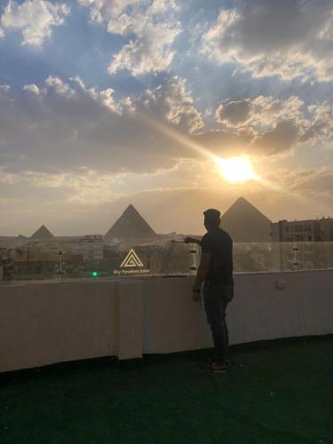 a man standing on a balcony looking at the pyramids at Najm Pyramids View in Cairo