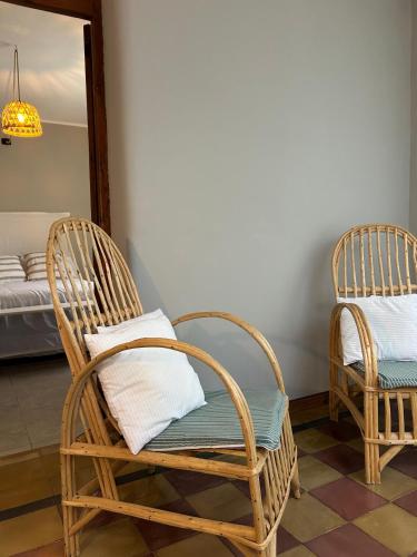 twee rieten stoelen in een kamer met een bed bij Casita de Barrio in Lobos