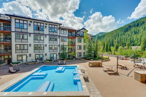 a hotel with a swimming pool in front of a building at Ski-InandSki-Out Winter Park Condo with Balcony in Winter Park