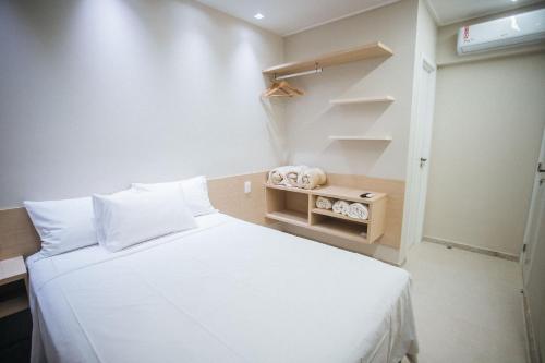 ein kleines Schlafzimmer mit einem weißen Bett und Regalen in der Unterkunft Brisa Muro Alto - Flat na Praia in Ipojuca