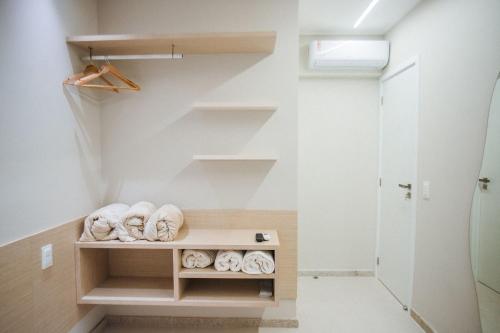 einen begehbaren Kleiderschrank mit weißen Wänden und Regalen in der Unterkunft Brisa Muro Alto - Flat na Praia in Ipojuca