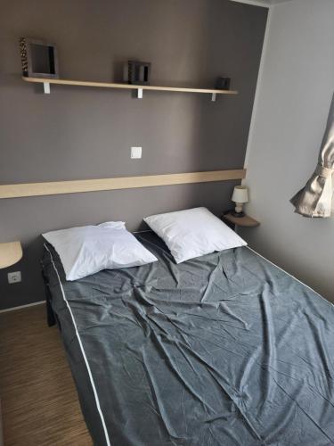 a bed with two pillows on it in a room at Mobil-home chez MG in Sérignan