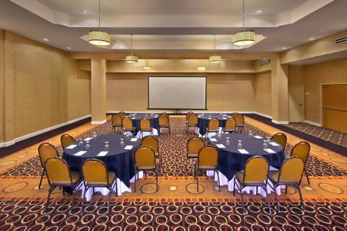 a conference room with tables and chairs and a screen at Holiday Inn Jacksonville E 295 Baymeadows by IHG in Jacksonville