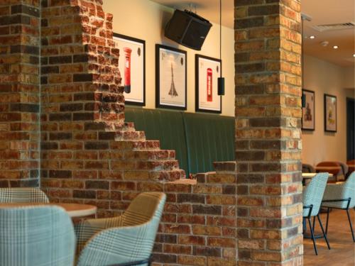 a brick wall with chairs and tables in a restaurant at B&B HOTEL Warrington in Warrington
