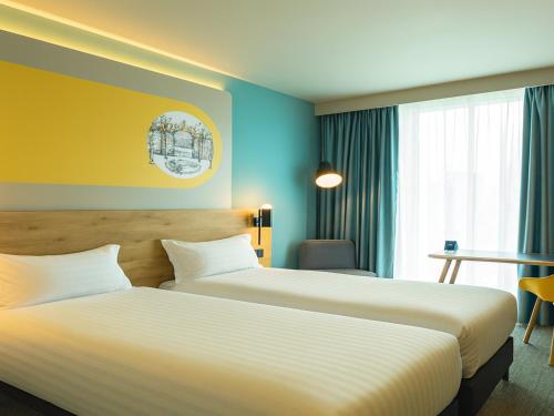 two beds in a hotel room with blue and yellow walls at B&B HOTEL Warrington in Warrington