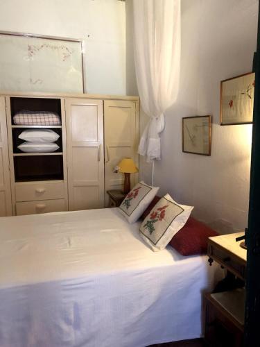 a small bedroom with a white bed with two pillows at Casa rústica com jardim privado in Tavira