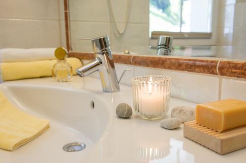 a bathroom sink with a soap dispenser and a candle at Hotel Krone Großarl in Grossarl