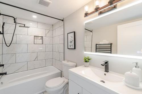 a white bathroom with a tub and a toilet and a sink at The Millertime Experience in Brantford