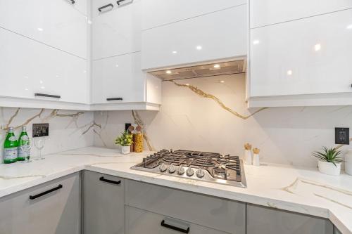 a white kitchen with a stove and white cabinets at The Millertime Experience in Brantford