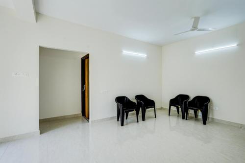 a row of black chairs in a white room at Hotel O Eswar Guest House Padur in Chennai