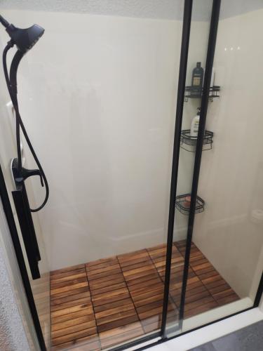 a shower with a glass door with a wooden floor at Paradise home with king bed & room for the family in Lake Havasu City