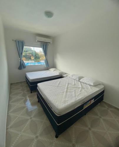 two twin beds in a room with a window at Cacao's Guaibim Residence in Valença