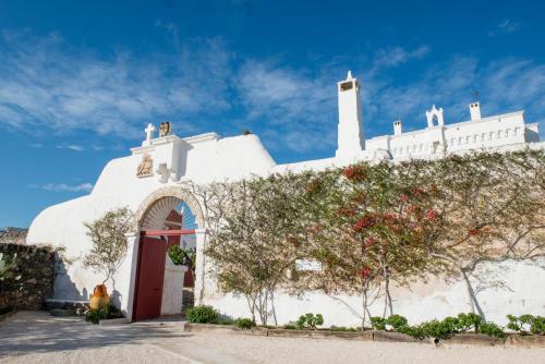 a white church with a red door and trees at Masseria Torre Coccaro in Savelletri di Fasano