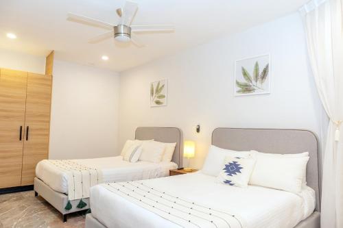 two beds in a room with white walls at It Beach Condo in Playa del Carmen