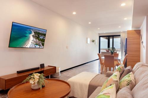 a living room with a couch and a tv on a wall at It Beach Condo in Playa del Carmen