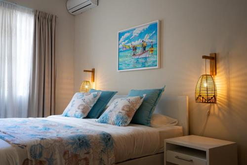a bedroom with a bed with blue pillows at Villa Pwani in Baie du Tombeau