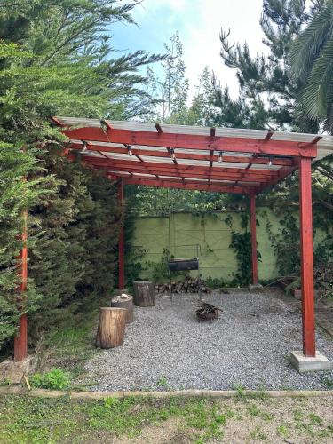 a red pergola with a bench in a yard at Casa en el Tabo 3 dormitorios 1 baño, Villa Cerrada, a 2 cuadras de la Playa Chepica in El Tabo