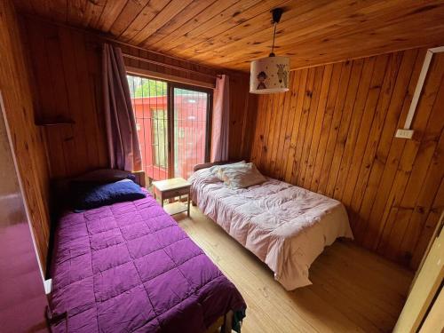 a bedroom with two beds in a wooden cabin at Casa en el Tabo 3 dormitorios 1 baño, Villa Cerrada, a 2 cuadras de la Playa Chepica in El Tabo