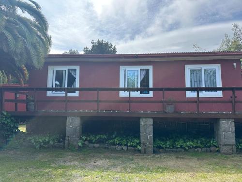 a red house with white windows and a bridge at Casa en el Tabo 3 dormitorios 1 baño, Villa Cerrada, a 2 cuadras de la Playa Chepica in El Tabo