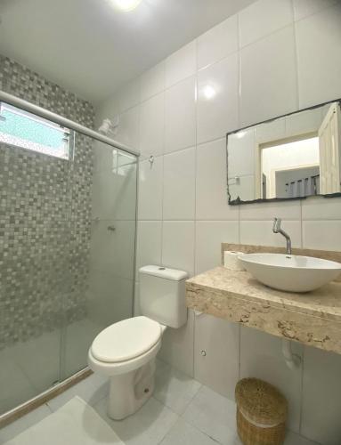 a white bathroom with a toilet and a sink at Cacao's Guaibim Residence in Valença