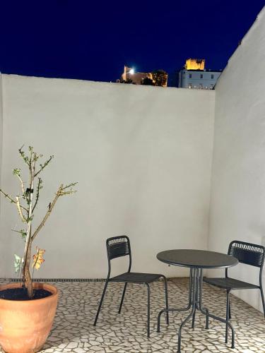 two chairs and a table and a potted tree on a patio at Habita Estremoz in Estremoz